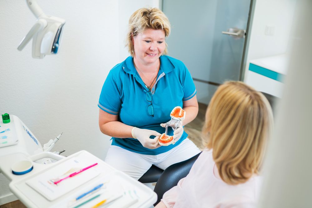 Unser Zahnarztpersonal erklärt einer Patientin bei der zahnmedizinischen Prophylaxe das Zahnschema.