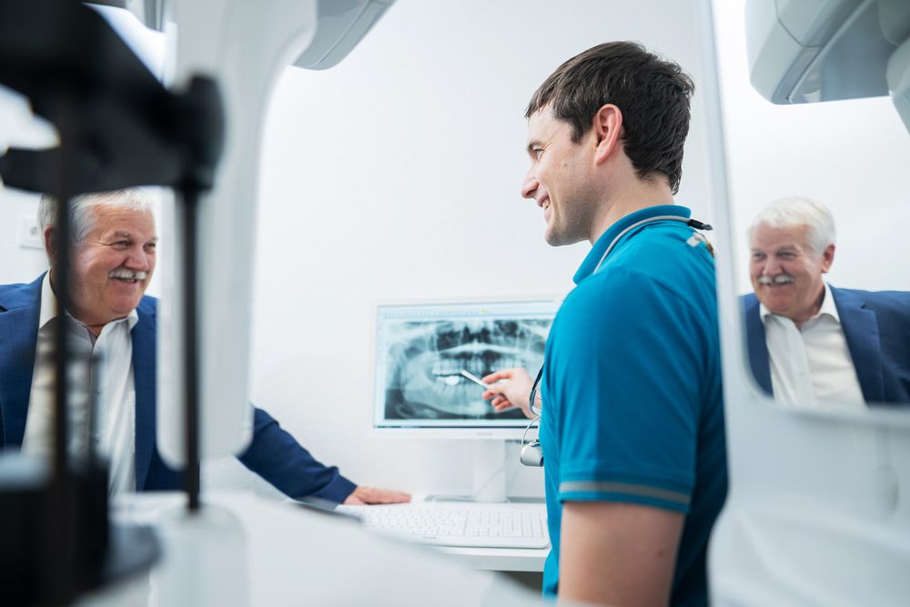 Zahnarzt Dr. Polgart bespricht mit einem Patienten das Röntgenbild.